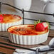 Two desserts in a white Acopa stoneware dish with a brown crust and strawberries on top.