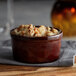 An Acopa Keystone chestnut stoneware ramekin filled with food on a table.