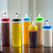 A group of six Tablecraft clear squeeze bottles on a table.