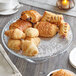 A glass plate with 12" silver foil lace doilies and croissants on it.