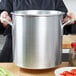 A woman holding a large Vollrath silver stock pot.