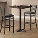 A Lancaster Table & Seating bar table with espresso finish and cast iron base plate with two chairs.
