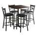 An espresso wood butcher block table with 4 black chairs with black cushions.