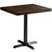 A Lancaster Table & Seating dining table with a wooden butcher block top and black metal base.