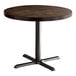 A Lancaster Table & Seating round wooden table with a cast iron base plate.