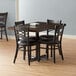 A Lancaster Table & Seating wood butcher block dining table with 4 black chairs.