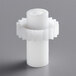 A white plastic knob with a black top and a nut on a gray surface.