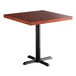 A Lancaster Table & Seating square wood table with a mahogany top and black cast iron base.