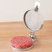An American Metalcraft hamburger patty being pressed with a round metal container.