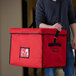 A man carrying a large red Cambro insulated delivery bag with a black strap.