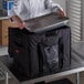 A chef putting a metal tray into a Cambro GoBag on a counter.