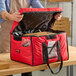 A man using a red Cambro Jumbo Delivery GoBag to carry a pizza.