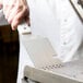 A hand holding a Star CG-S Panini Grill Spatula over a grill.