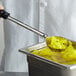 A person using a Vollrath black perforated stainless steel Spoodle to serve pineapple slices.