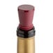 A bottle of wine closed with a Franmara burgundy wine stopper with gold trim.