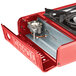 A red Choice portable gas range with a brass burner on a metal counter.
