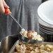 A person using an orange Vollrath Spoodle to serve mashed potatoes.