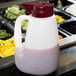 A white Tablecraft dispenser with a red lid filled with purple liquid.