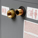 A close-up of brass fittings on a gray Hatco water heater box.
