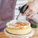 A person using a Sterno butane torch to smudge a cake.