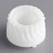 A white plastic object with a circular pattern and a hole in the center.