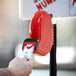A hand holding a blue ticket in a red Garvey My Turn take-a-number machine.
