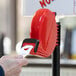 A person holding a red Garvey My Turn ticket dispenser with a white ticket in it.