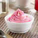 A white Dart foam bowl filled with pink frosting.