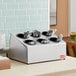 A Steril-Sil stainless steel countertop flatware organizer with black cylinders holding silverware.