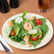 A Homer Laughlin ivory china plate with a salad and shrimp.