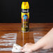 A person using SC Johnson Pledge Moisturizing Furniture Oil Spray to clean a wooden table.