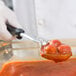 A person using a Vollrath black oval spoodle to serve food.