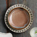 A white Libbey coupe bowl with brown spots on a table.