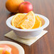 A white Nustone melamine bowl filled with orange slices.