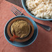 A bowl of rice with brown powder and a wooden spoon.