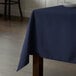 A wooden table with a rectangular navy blue Intedge tablecloth on it.