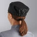 A woman wearing a black Choice chef hat at a kitchen counter.