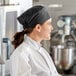 A woman in a chef's uniform and black Choice mesh top chef hat.
