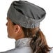 A person wearing a Choice Houndstooth chef skull cap with a black and white checkered pattern.