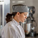 A woman wearing a Choice Houndstooth Mesh Top Chef Skull Cap.