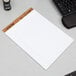 A TOPS white legal pad with wide ruled lined paper on a desk with a keyboard.