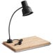 An Avantco black carving station heat lamp with a black cord and wooden tray on a table.