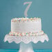 A white cake with a silver glitter "7" on top.