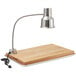 An Avantco stainless steel carving station lamp on a wooden cutting board.