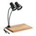 A carving station kit with a dual arm black heat lamp, wooden cutting board, and drip pan.