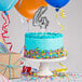A white birthday cake with a silver number four balloon on top.