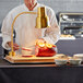 An Avantco chef uses a carving station to cut a large piece of meat.