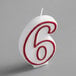 A white birthday candle with a red outlined number six.
