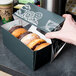 A hand holding a box of donuts with a drawing of a cup of coffee on it.