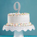 A white cake with a silver number nine on top.